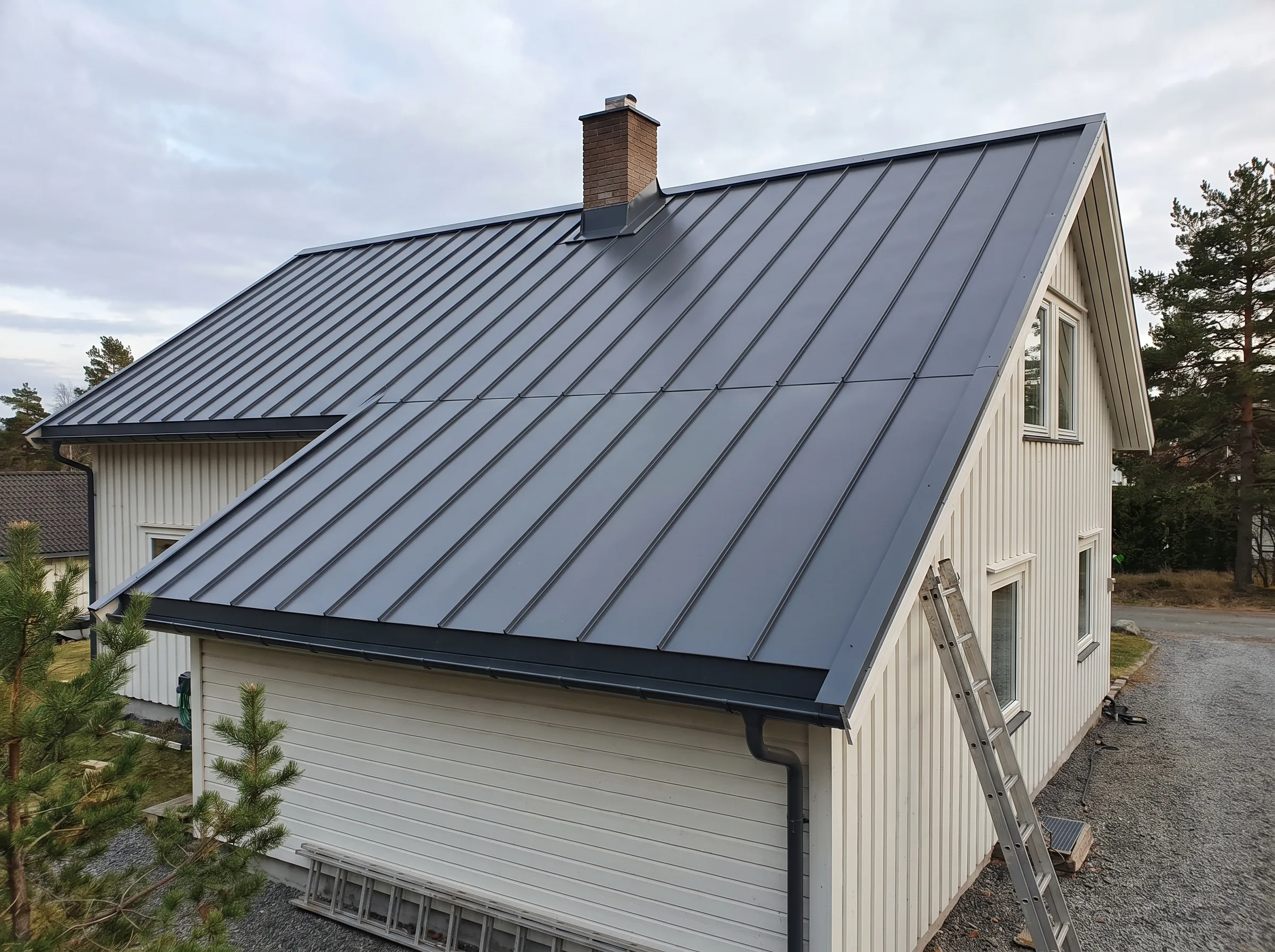 Taktekking med moderne takplater og godt håndverk på et hus i nydelig natur