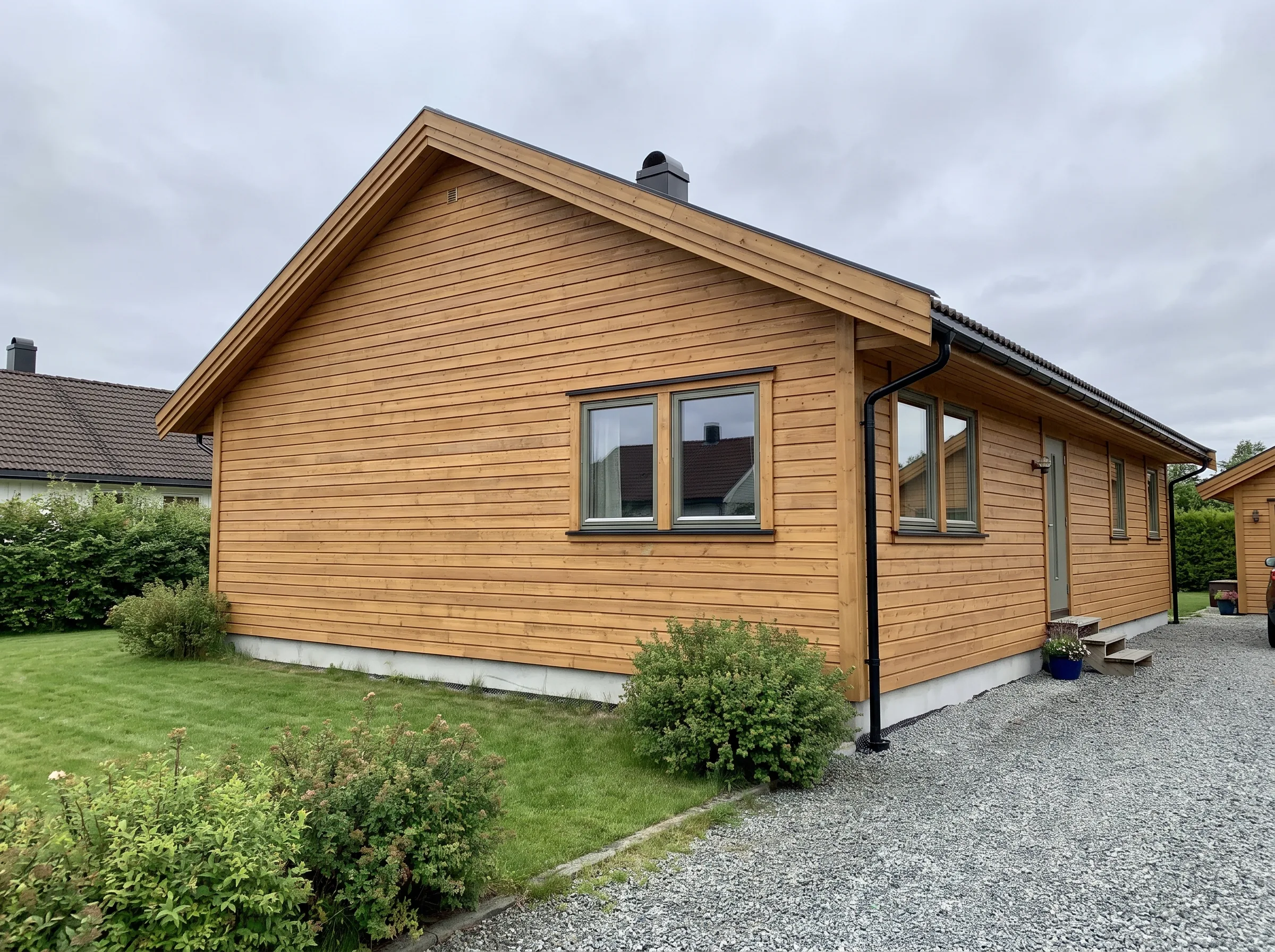 Moderne hus med trepanel og grønt hageområde