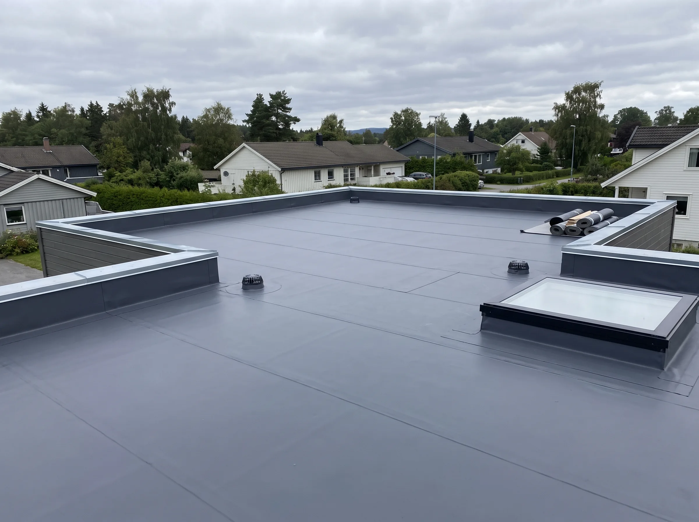Flatt tak med takvinduer og ventilasjonssystem i bakgrunnen
