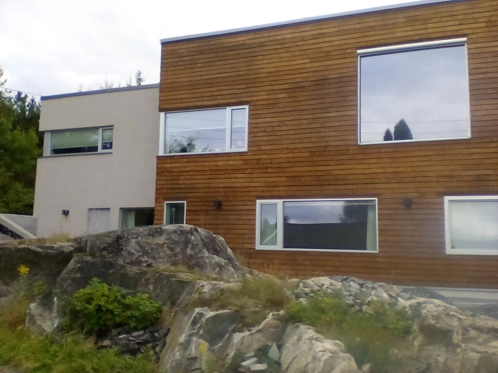 Moderne hus med trevinduer og trepanel, ligger i naturskjønt område