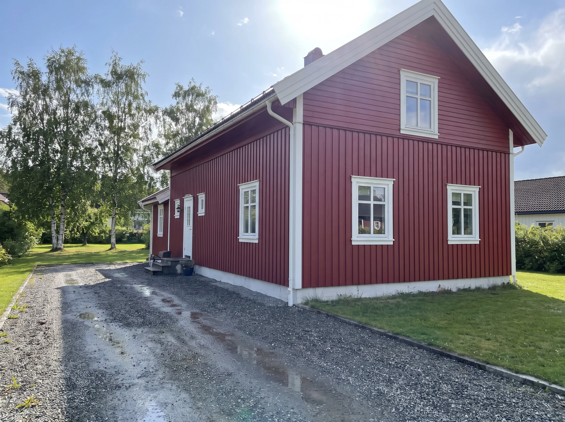 Rødt hus med hvit kledning, enkel inngang og steinlagt oppkjørsel