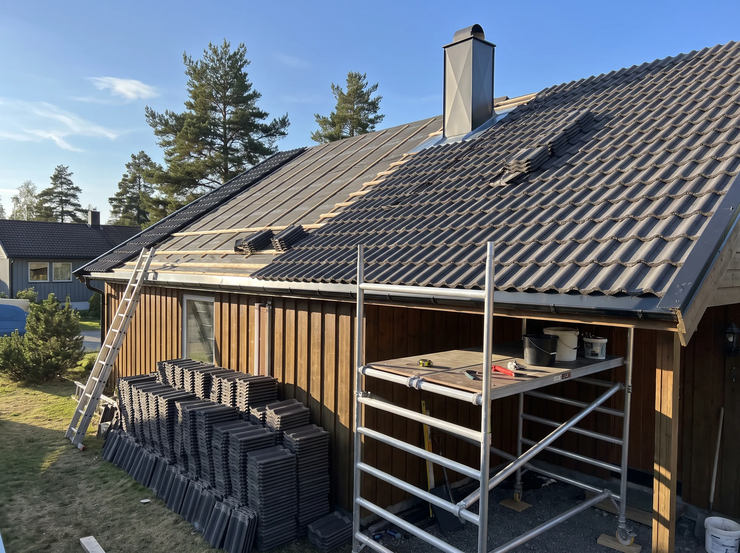 Taktekking på hus med nye takstein og stillas i forgrunnen