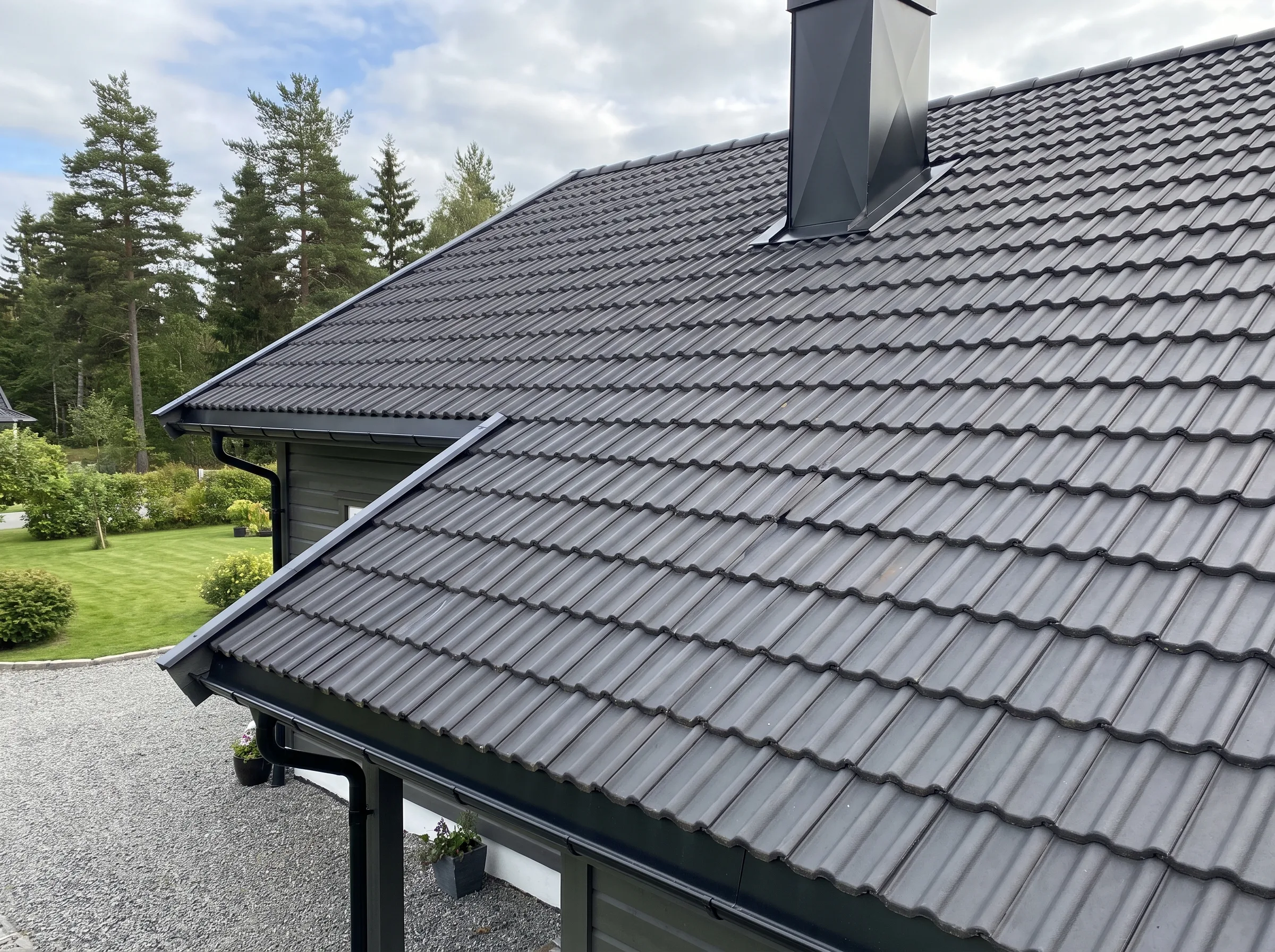 Taktekking med moderne takstein og pent hageområde i bakgrunnen