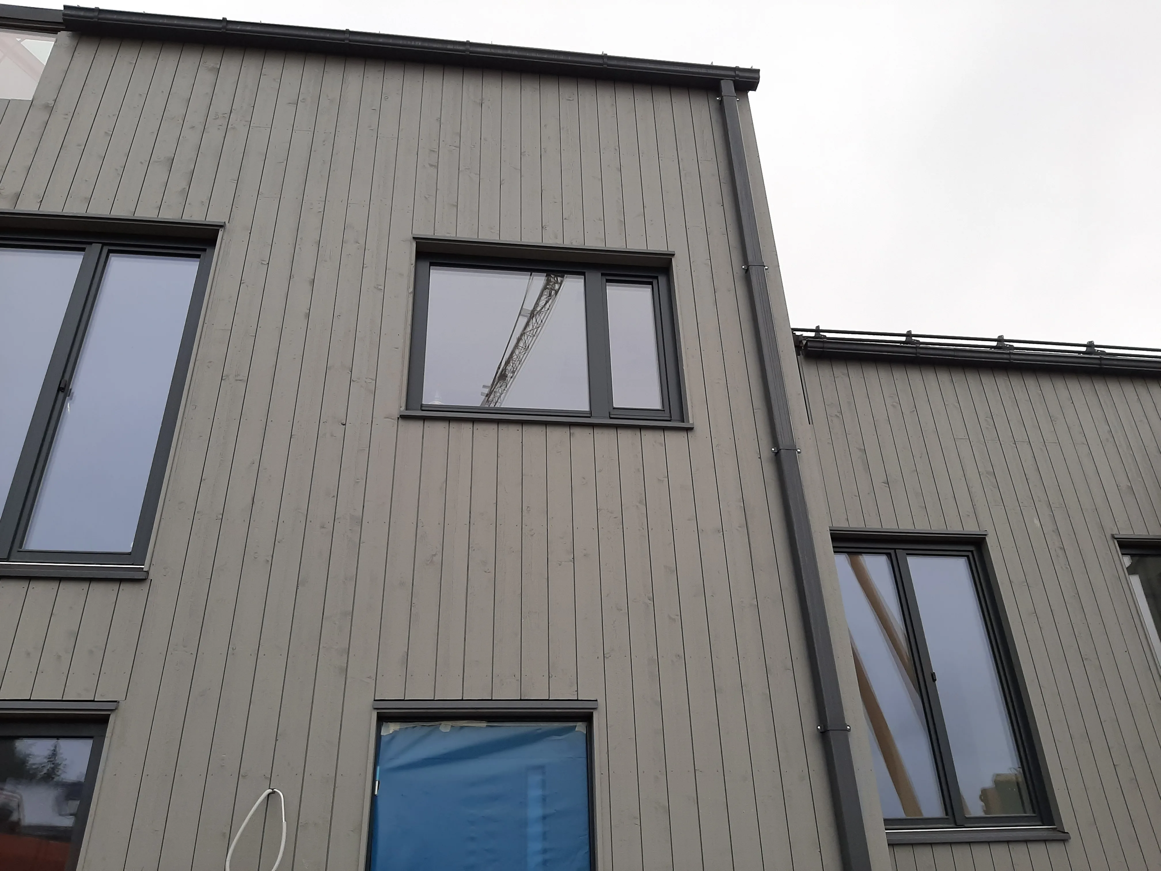 Fasadearbeid på en moderne bygning med trepanel og vinduer