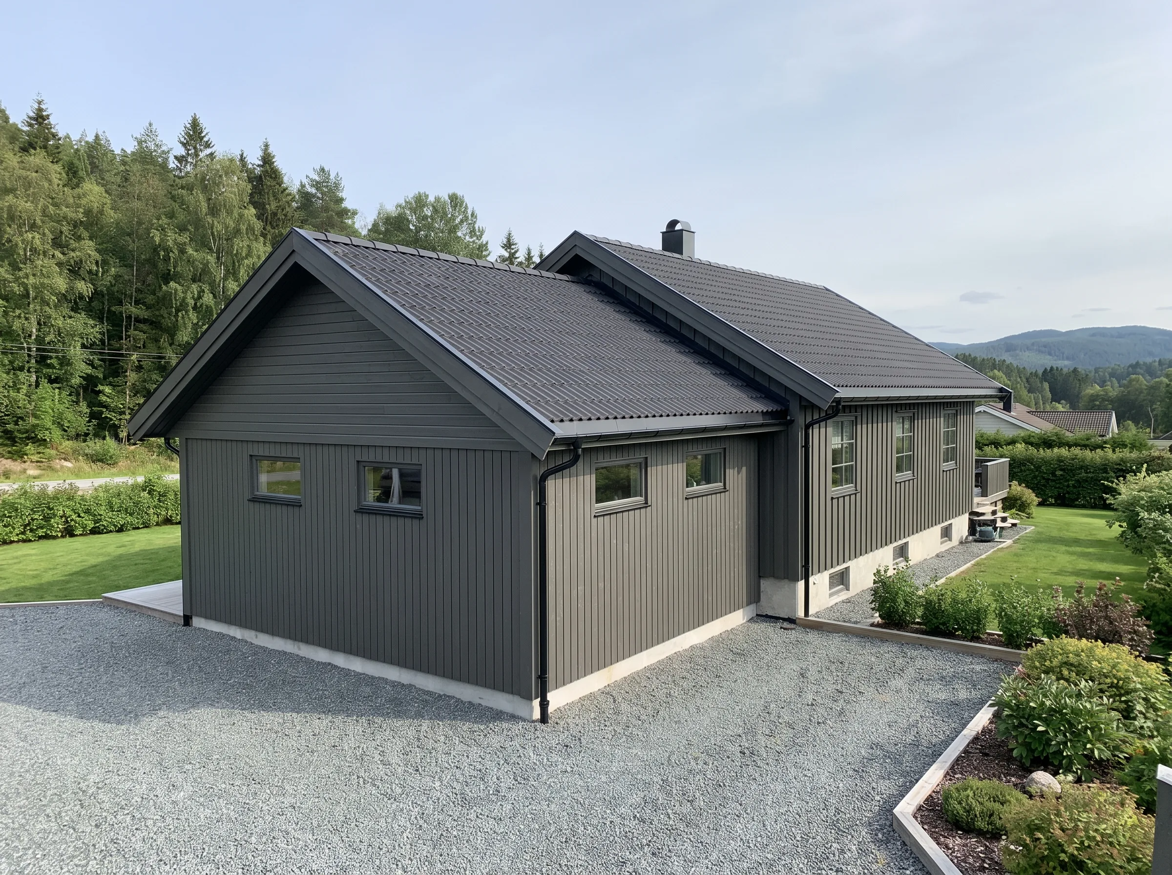 Modern enebolig med gråkledning, plen og blomsterbed i hagen